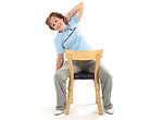 Jumppaaja istuu tuolilla kasvot selkänojaa kohti jalat haara-asennossa