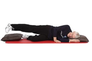 Jumppaaja makaa vasemmalla kyljellään jumppamatolla lattian puoleisen polven ollessa koukussa ja nostaa oikeaa jalkaa suorana ylöspäin kantapää edellä irti nilkan alla olevasta tyynystä.