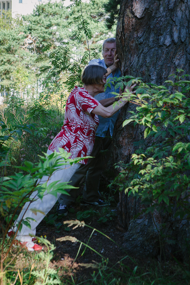 Kaksi jumppaajaa seisoo metsässä ja ovat punnertamassa puuta vasten vieden kyynärpäitä koukkuun vartalon sivuille