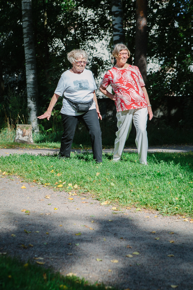 Kaksi ruohikolla seisovaa jumppaajaa astunut vasemmalla jalalla pitkän askeleen eteen polven ollessa koukussa ja oikea jalka on takana ojennettuna.