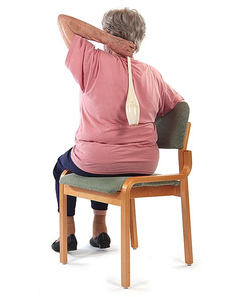 Jumppaaja istuu tuolilla ja on vienyt vasemman käden koukussa niskan taakse pitäen keilaa kädessään.