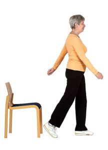 Jumppaaja on tuolilta nousun jälkeen lähtenyt kävelemään ottamalla vasemmalla jalalla askeleen eteenpäin. Oikea käsi on heilahtanut eteen ja vasen taakse rytmittäen kävelyä.