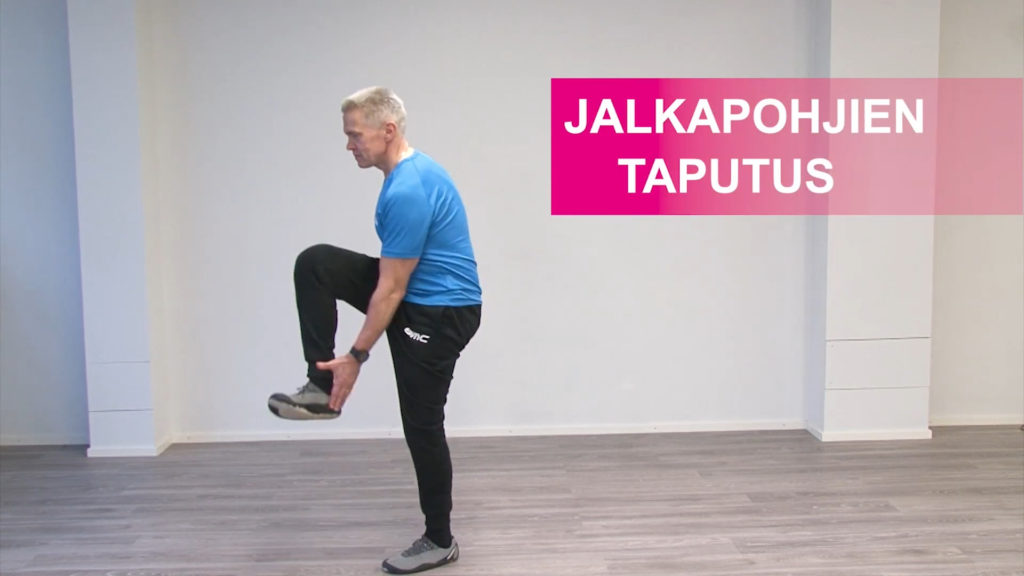Jumppaaja seisoo yhdellä jalalla ja on nostanut toisen jalan koukussa eteen ilmaan. Koskee vastakkaisella kädellä jalkapohjaa.